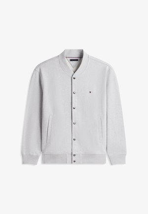 Helehall nuppudega bomber-jope soonikkoelise krae, mansettide ja äärega, vasakul rinnal väike Tommy Hilfigeri logo ning kaks eesmist taskut.