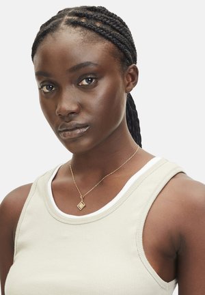 Beige geribbelde tanktop met witte rand, met daarin een delicate gouden ketting met een diamantvormige hanger. Gladtextuur huid en gevlochten haar.