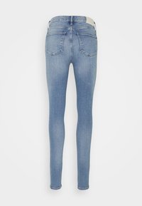Jeans ajustados de color azul claro con una cintura alta, que presentan una textura suave, cinco bolsillos y una etiqueta en la parte trasera de la cintura.