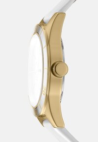 Orologio dorato con quadrante bianco, caratterizzato da una cassa rotonda liscia, cinturino bianco e una corona prominente. Design minimalista con marcature chiare.