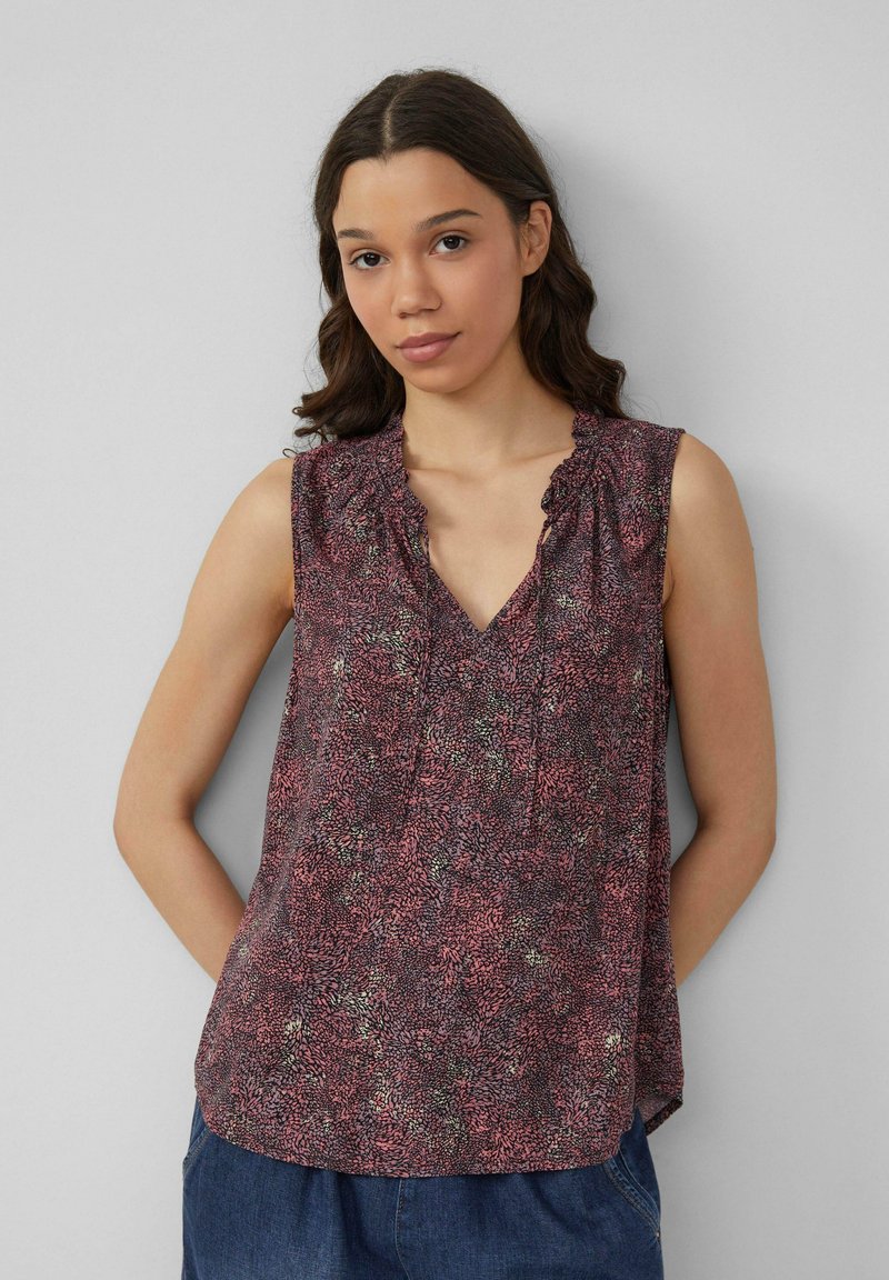 Mouwloze top met V-hals en een rimpelnek, met een roze en groene bloemenprint op een donkere achtergrond. Lichtgewicht stof.