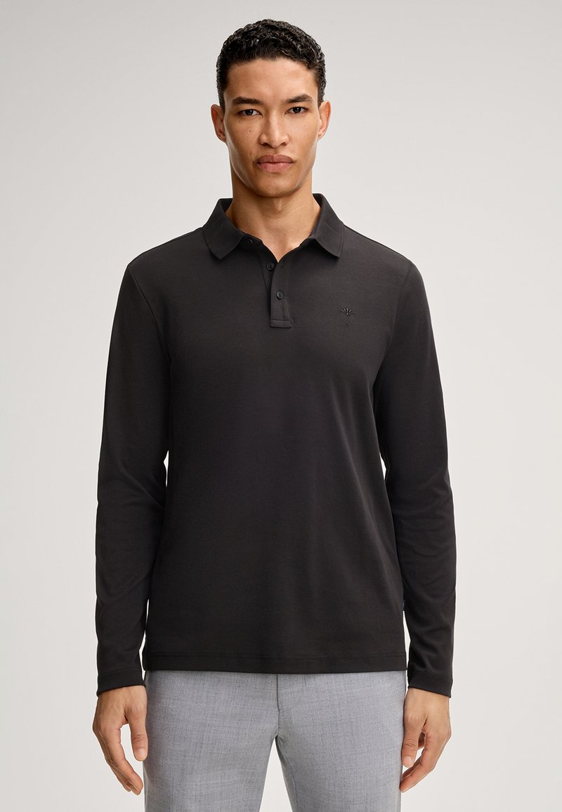 Schwarzes Langarm-Polohemd mit Kragen, Knopfleiste und dezentem Logodetail. Der Stoff wirkt glatt und dehnt sich sanft.
