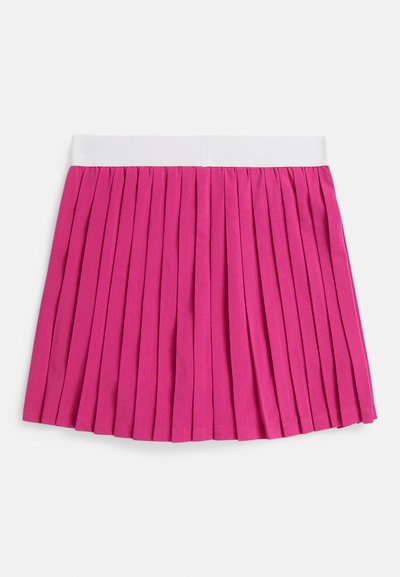 Πλισέ φούστα σε έντονο ροζ χρώμα, με λευκή μέση. Το ύφασμα φαίνεται λείο με κάθετες πτυχές που εκτείνονται από την κορυφή μέχρι το κάτω μέρος.
