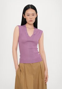 Purple sleeveless top with a V-neck, ribbed texture, and cut-out details, paired with a high-waisted, striped brown skirt.