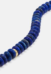Colar de contas de lápis-lazúli com contas redondas e em forma de disco alternadas em azul profundo, realçadas por uma conta de destaque dourada.