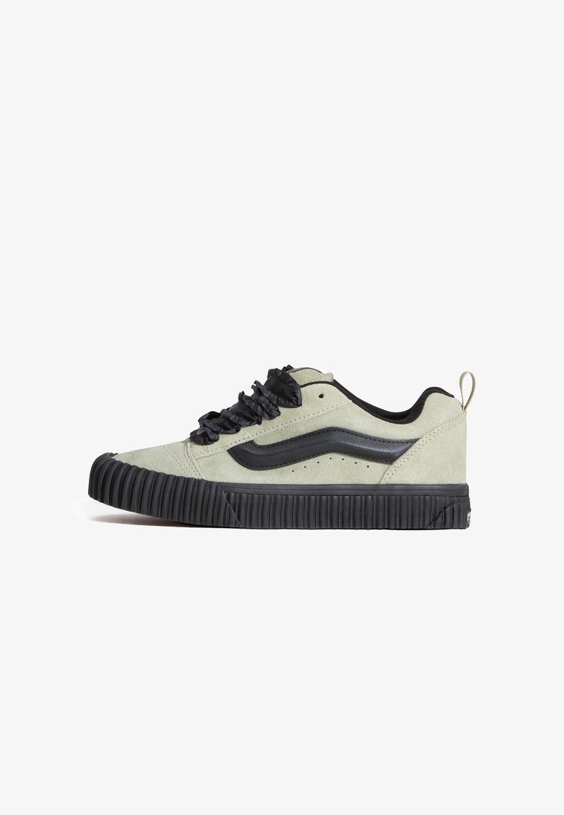 Baskets basses en daim gris clair avec semelle en caoutchouc noire, détail vague noir sur le côté, lacets noirs et languette au talon.