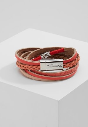 Lederwickelarmband in den Farbtönen Hellbraun und Koralle mit geflochtenem Detail und einem silbernen Verschluss, graviert mit "Tamaris", präsentiert auf einer weißen Oberfläche.