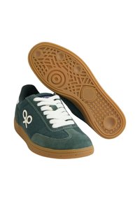 Zapatillas de ante verde y pana con cordones blancos, suela de goma marrón, patrones de banda intrincados y detalle del logo en el costado.