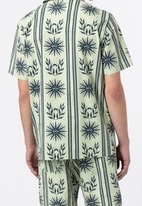 Ljusgrön kortärmad skjorta med marinblå blommönster och solstrålar, med horisontella ränder och en avslappnad passform.