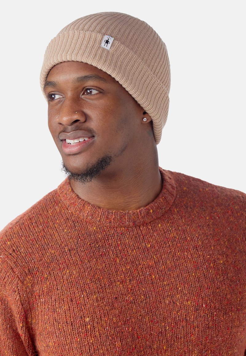 Berretto in maglia color beige con texture a coste e una piccola etichetta logo. Maglione rosso caldo con effetto marmorizzato, collo rotondo e tessuto texture.