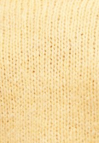 Κοντινό πλάνο απαλής, κρεμ χρωματισμένης πλεκτής μάλλινης ύφανσης με υφή από μοτίβο ραφής.