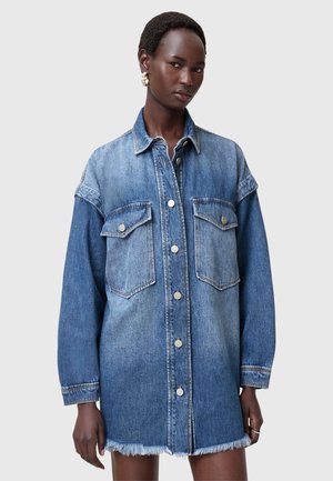 Abito camicia in denim con una sfumatura dal blu chiaro al blu scuro, grandi tasche frontali, bottoni argentati e orlo sfrangiato. Presenta maniche lunghe e una vestibilità rilassata.
