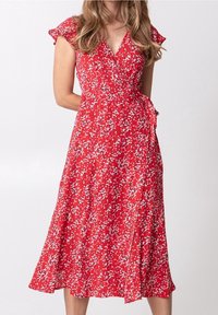 Rotes, blumiges Wickelkleid mit kurzen, fransigen Ärmeln und einem Bindeband in der Taille. Leichter Stoff und mittellanger Saum.
