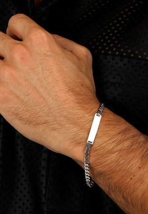Silberne Kettenarmband mit einem rechteckigen flachen Anhänger. Es hat ein geflochtenes Design, eine glatte Oberfläche und ein poliertes Finish. Die Textur ist glänzend.