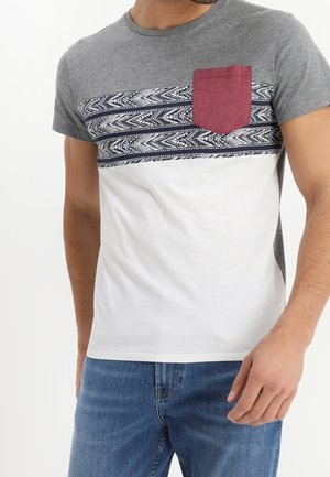 Grå og hvid T-shirt med et mønstret brystpanel og en mørkerød lomme. Stoffet er glat og ligner bomuld. Kortærmet.