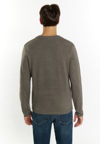 Maglione grigio a maglia con scollatura rotonda e maniche lunghe, abbinato a jeans in denim blu. La texture è a coste e liscia.