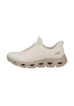Zapatilla beige Skechers Glide-Step con parte superior de malla, cierre de cordones, cuello acolchado y suela gruesa con múltiples recortes ovalados.
