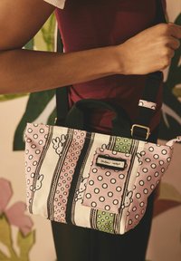 Borsa in tela con strisce rosa, nere e verdi. Presenta pois bianchi e motivi di coniglietto. Include una piccola tasca frontale e una tracolla regolabile.