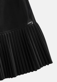 Czarna plisowana spódnica wykonana ze skóry ekologicznej, z gładkim górnym fragmentem i fakturowanymi plisami, z małą metką marki po boku.