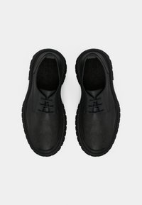 Μαύρα δερμάτινα παπούτσια με λεία υφή, στρογγυλή μύτη, σχέδιο με κορδόνια και χοντρή ελαστική σόλα.