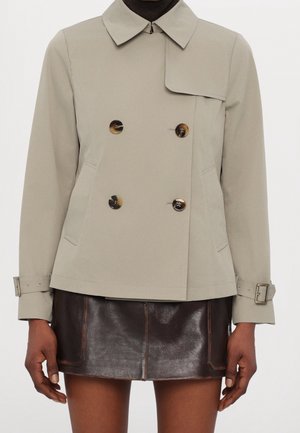 Dobbeltbrystet grå trenchcoat med bred krave, store knapper og bælteved cuffs; parret med en bronze-farvet lædernederdel.