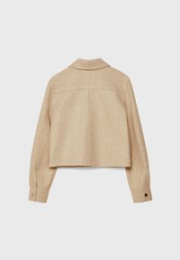 Chaqueta corta de lana beige con cuello estándar, puños abotonados y textura suave con detalles mínimos de costura en la parte trasera.