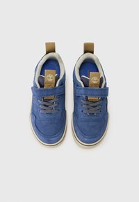 Baskets en daim bleu avec une sangle beige, des lacets texturés et des semelles en caoutchouc. Dotées d'une étiquette logo sur la languette et d'une doublure intérieure contrastante.