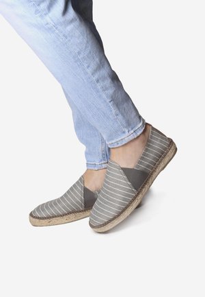 Espadrilles rayadas gris con una suela de yute texturizada y un upper de lona, que presentan un corte elástico en forma de V para un diseño de fácil calzado.