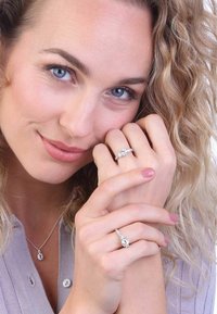 Les bijoux en argent comprennent une bague avec une pierre ovale et un anneau texturé, assortie d'un pendentif correspondant. Le mannequin exhibe deux bagues sur les mains.