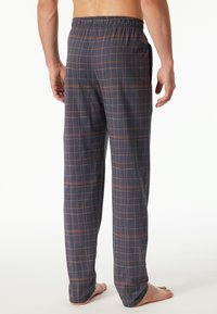 Men's plaid pajama pants in navy with orange and cream grid pattern, elastic waistband, lightweight fabric, and side pockets.