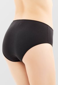 Slip in cotone nero con una texture liscia, design a vita media e waistband elastico. Presenta uno stile minimalista senza motivi o accessori.