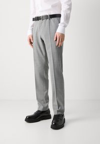 Pantaloni grigi su misura con una finitura testurizzata, abbinati a una cintura nera e scarpe nere, caratterizzati da una silhouette a gamba dritta.