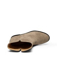 Beige mockask stövlett med rund tå och öppen design. Inuti finns en slät läderfoder. Svart gummisula.