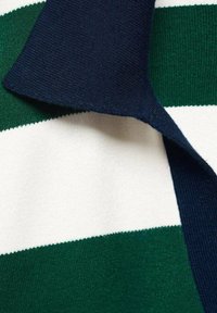 Tessuto a maglia a righe verdi e bianche con colletto blu navy. La texture è liscia e morbida, con un classico design a coste.