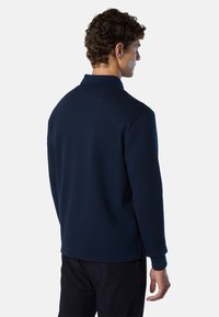 Camisa polo de manga larga en azul marino con un acabado texturizado. Presenta un cuello clásico y aberturas laterales en el dobladillo para mayor comodidad.
