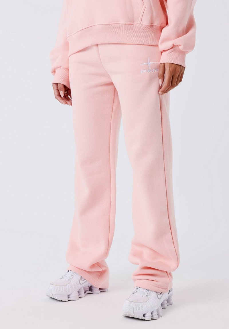Roze joggingsbroek van zacht, gestructureerd materiaal met een relaxte pasvorm, voorzien van een geborduurd logo en gecombineerd met witte chunky sneakers.