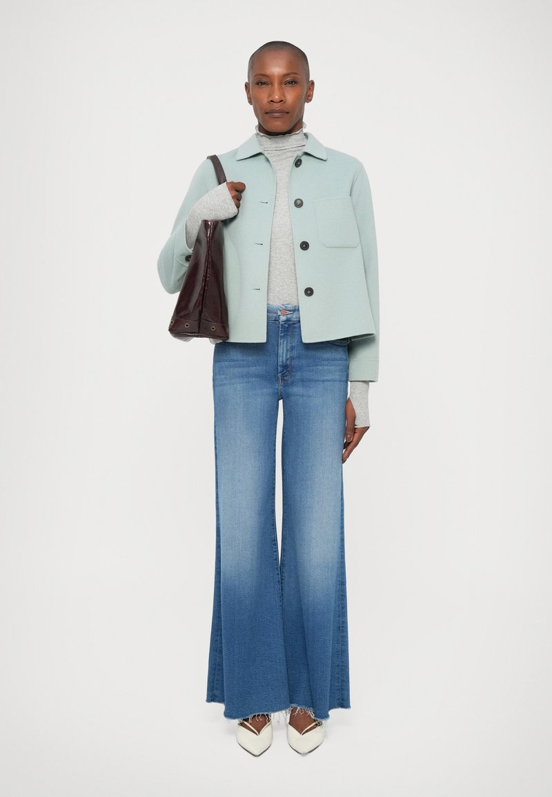Mint green collared jacket, gray turtleneck, flared light blue jeans, and white shoes with a dark brown handbag. Smooth textures and clean lines.