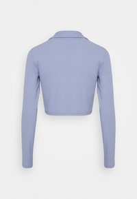 Kortärmad topp med lång ärm i ljusblå ribbad tyg. Har en klassisk krage och en figurnära design med en slät yta.