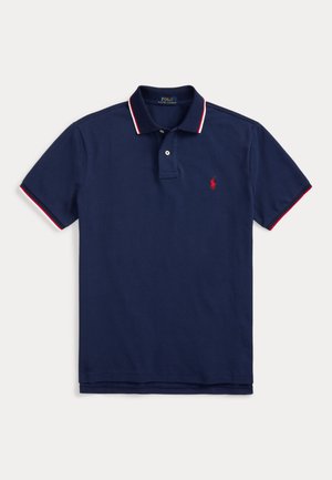 Polo azul-marinho feito de algodão, apresentando um fecho de três botões, colarinho listrado em vermelho e branco, e um pequeno logotipo bordado no peito.