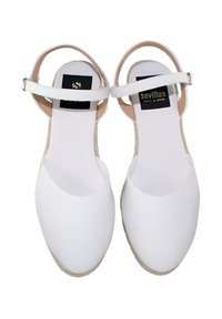 Sandalias blancas de punta cerrada con tiras en el tobillo y suelas envueltas en yute, con la etiqueta "sevillas" en las plantillas, vistas desde arriba.