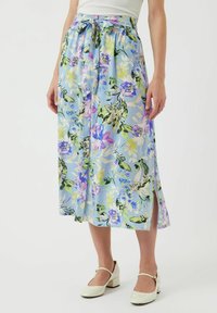 Blommig maxikjol i ljusblått tyg med lila och gröna mönster, med en knytbar midja och en sidoklyvning för ökad rörelse.