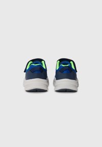 Chaussures de sport bleu marine avec semelles grises, dotées d'accents vert fluo et d'un matériau en maille texturée, avec un talon arrondi et une sangle ajustable.