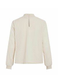 Langærmet creme bluse med et struktureret polka dot mønster, nøglehulslukning bagpå og samlede manchetter. Blødt stof med en afslappet pasform.