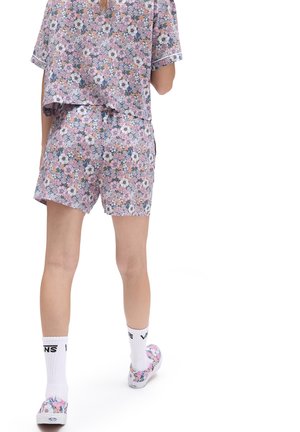 Ensemble de top court et de shorts à imprimé floral dans des couleurs pastel. Le matériau est léger avec une coupe décontractée. Accentué par des bordures blanches et des motifs vifs.