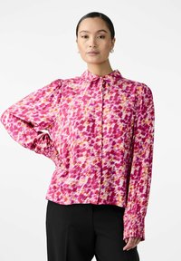 Pink and orange patterned blouse with long sleeves, buttoned collar, and gathered cuffs. Made of lightweight fabric, relaxed fit.