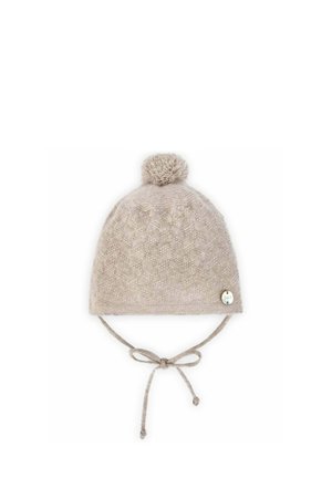 Chapeau d'hiver en tricot beige avec un pompon sur le dessus, texture à motifs et liens latéraux. Étiquette de marque décorative sur le côté.
