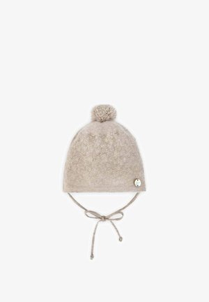 Chapeau d'hiver en tricot beige avec un pompon sur le dessus, texture à motifs et liens latéraux. Étiquette de marque décorative sur le côté.