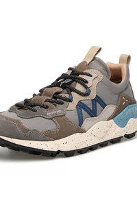 Baskets multicolores avec des panneaux beige, gris et bleu, lacets noirs, semelle épaisse mouchetée et languettes en tissu sur la languette et le talon.