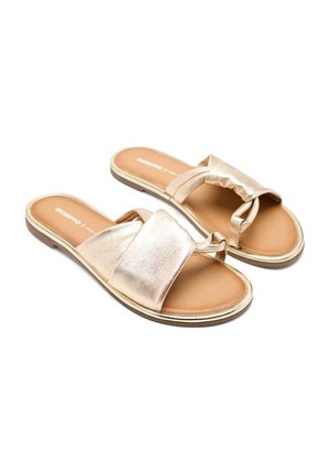 Złote metaliczne płaskie sandały o gładkim wykończeniu, z krzyżującymi się paskami i miękką, wyściełaną wkładką, z kontrastującą jasnobrązową podeszwą.