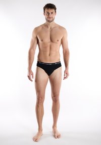 Black cotton briefs with a textured waistband featuring the "TOM TAILOR" logo in white. Classic design with a snug fit.